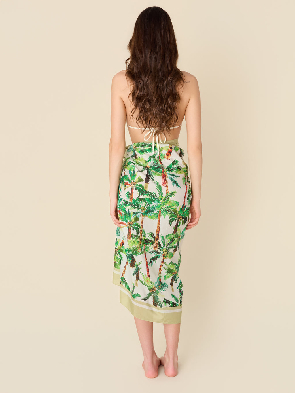 Green tropical palm print pareo made from a cotton-silk blend, designed as a beach cover-up or resort wrap.